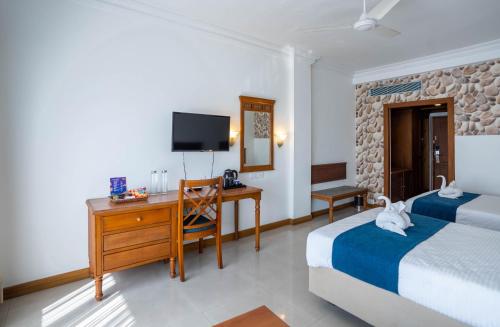 a bedroom with two beds and a desk and a tv at Casino Hotels Ltd in Trichūr