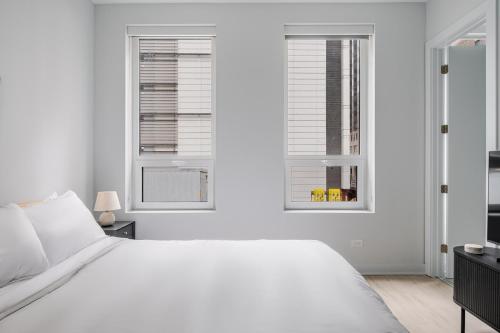 una camera bianca con un letto bianco e due finestre di Blueground The Loop elevator nr Willis Tower CHI-1236 a Chicago
