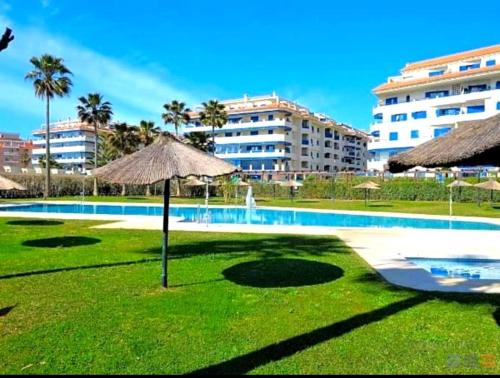 ein Swimmingpool mit Sonnenschirm und ein Resort in der Unterkunft Apartamento La Noria pie de playa Manilva in San Luis de Sabinillas