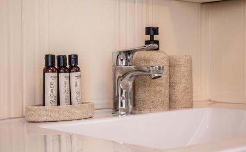 a bathroom sink with a faucet and three bottles of wine at No5 on Golden Sands in Margate