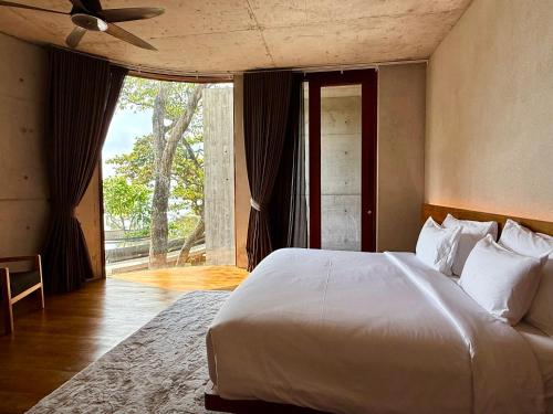 a bedroom with a white bed and a large window at Vows Villa Beachfront in Ban Bang Po