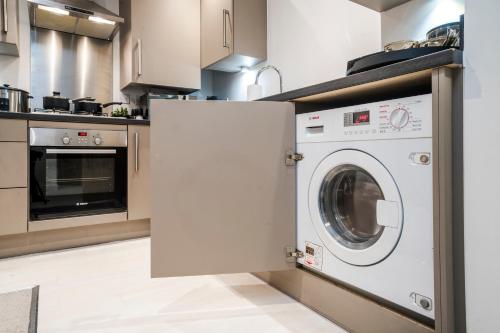 a kitchen with a washing machine in a kitchen at TheCountingSheep - Heathrow in 15 mins - Glass Balcony - Dedicated Workspace in Hounslow