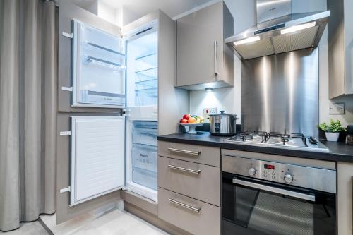 a kitchen with white cabinets and a stove top oven at TheCountingSheep - Heathrow in 15 mins - Glass Balcony - Dedicated Workspace in Hounslow