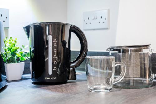 a black coffee pot sitting on a table next to a glass at TheCountingSheep - Heathrow in 15 mins - Glass Balcony - Dedicated Workspace in Hounslow