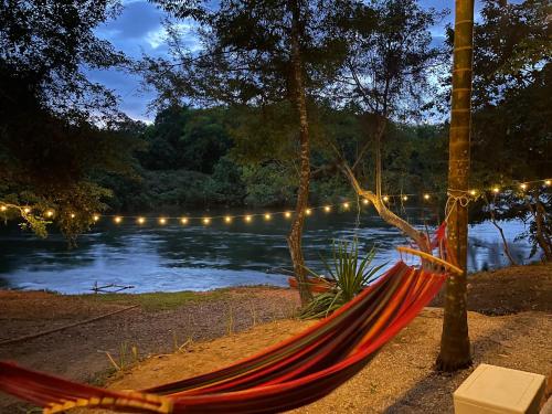 a hammock in front of a lake with lights at Khao Phang Camping in Ban Pha Saeng Lang