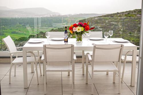 a white table with chairs and a vase of flowers at A52 - Apartment with Sea and Country Views in Mellieħa
