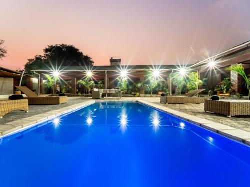 a pool with blue water at night with lights at Bishop House in Victoria Falls