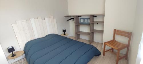 niewielka sypialnia z niebieskim łóżkiem i krzesłem w obiekcie Idéalement situé, tout à pied, 60m2 w mieście Saint-Georges-de-Didonne