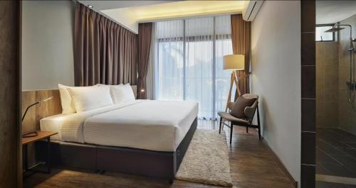 a bedroom with a bed and a chair and a window at Tropics Eight Suites in George Town