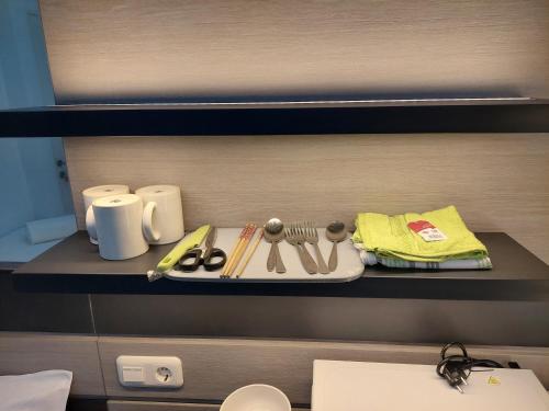 a shelf with a plate with utensils on it at Minimalist Studio Apartment (No Kitchen) at Aeropolis Residence By Travelio in Tangerang