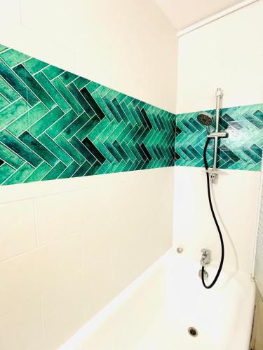 La salle de bains est pourvue de carrelage vert et blanc sur le mur. dans l'établissement Superbes Studios av Versailles a Paris 16, à Paris