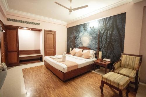 a bedroom with a bed with a painting on the wall at Casino Hotels Ltd in Trichūr