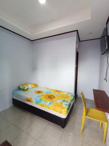 a bedroom with a bed and a table and a yellow chair at Agung Homestay And Foodie in Kalawas