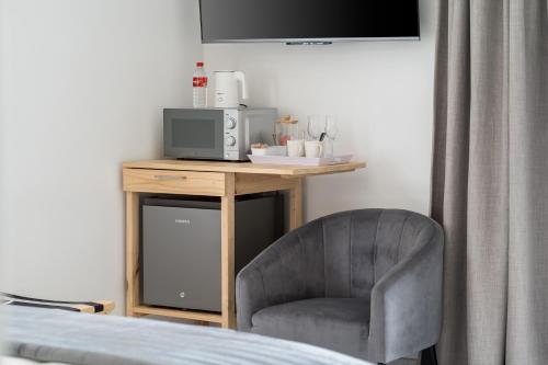 a bedroom with a chair and a table with a microwave at AnnaNella Boutique Hotel in Durbanville