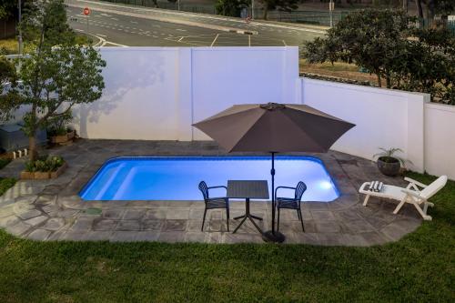 a table and an umbrella next to a swimming pool at AnnaNella Boutique Hotel in Durbanville