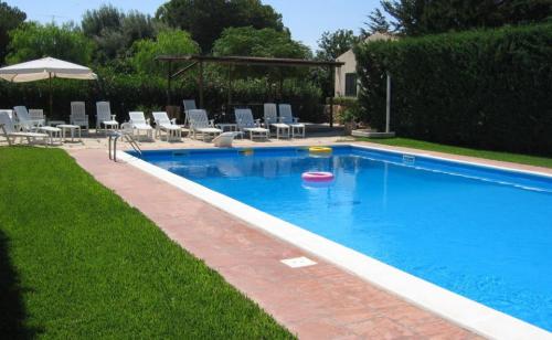 a large swimming pool with chairs and an umbrella at L'Araucaria turismo rurale in Santa Croce Camerina