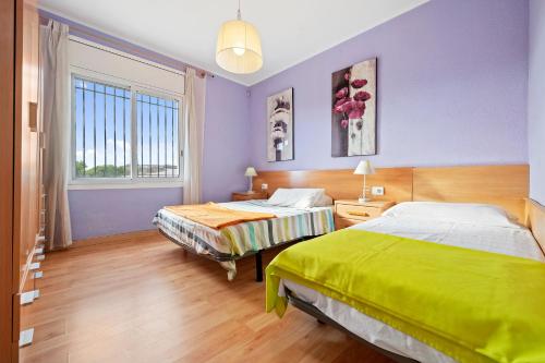 two beds in a room with purple walls at Caseta de l'avi in Camarles