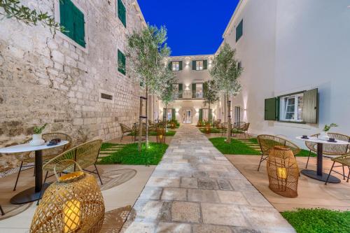 a courtyard with tables and chairs and a building at Hotel Brattia, Adults Only, Heated Pool, A la Carte Breakfast, Postira, Brač Island in Postira