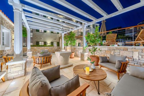 an outdoor patio with couches and tables at Hotel Brattia, Adults Only, Heated Pool, A la Carte Breakfast, Postira, Brač Island in Postira