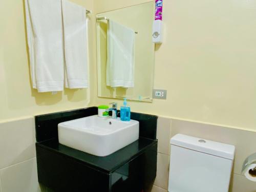 a bathroom with a white sink and a toilet at Azalea 1BR Suite - Pool, Gym, WiFi, Netflix, AC, Kitchen, Ayala Mall in Cebu City