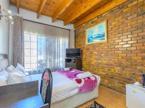 a bedroom with a bed and a brick wall at Royal Olympia Lodges & Safaris RSA in Sandton