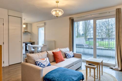 un salon avec un canapé et une grande fenêtre dans l'établissement Le Nicole un appartement en duplex avec balcon et place de parking, à Rouen