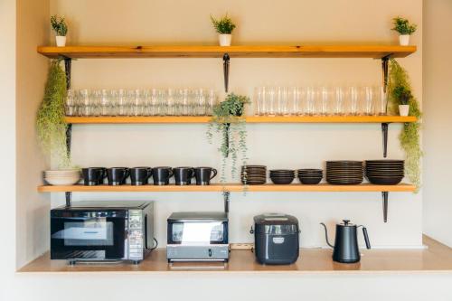 a kitchen with wooden shelves with glasses and a microwave at Azure Palace 伊豆高原 in Ito