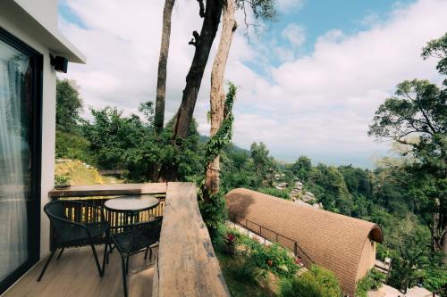 a balcony with a table and chairs and a view at Baan Nhuer Mek บ้านเหนือเมฆ Coffee and Desk on the Cloud in Ban Pang Klang
