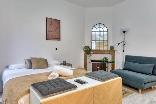 une chambre avec un grand lit et une chaise bleue dans l'établissement L'Écrin Normand un studio au cœur de Rouen, à Rouen