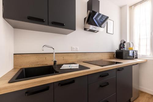 a kitchen counter with a sink and a microwave at LA SUITE HUIT DU BRAS D'OR in Boulogne-sur-Mer