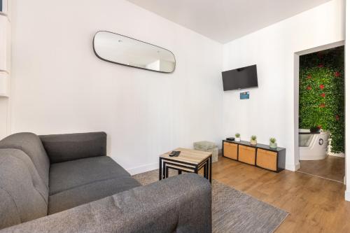 a living room with a couch and a tv at LA SUITE HUIT DU BRAS D'OR in Boulogne-sur-Mer