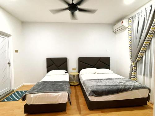 two beds in a room with a ceiling fan at ALEXIS VILLA Whole OR Room in Muar