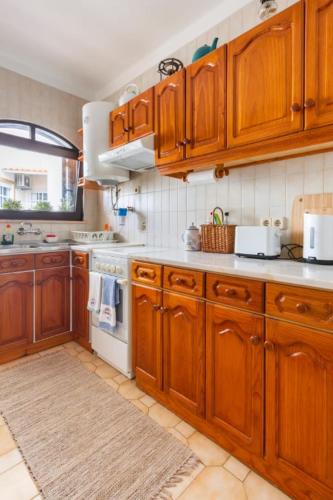 a kitchen with wooden cabinets and a stove top oven at Casa das Andorinhas in Ferragudo