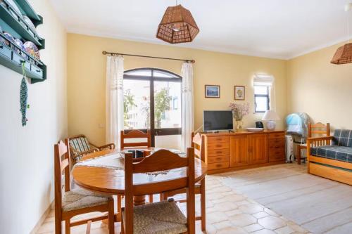 een woonkamer met een tafel, stoelen en een televisie bij Casa das Andorinhas in Ferragudo