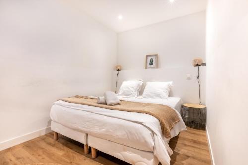 a bedroom with a bed with white walls and wooden floors at LA SUITE SEPT LE BRAS DOR in Boulogne-sur-Mer