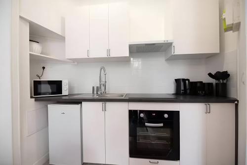 une cuisine blanche avec un évier et un micro-ondes dans l'établissement TBS 316 - Apartment close to Eiffel Tower, à Paris