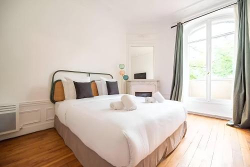 Cette chambre comprend un grand lit blanc et une grande fenêtre. dans l'établissement TBS 316 - Apartment close to Eiffel Tower, à Paris