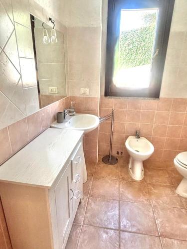 a bathroom with a sink and a toilet and a window at Nura Bilo 2 in San Teodoro
