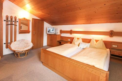 a bedroom with a large bed and a chair at Gästehaus Rass in Lofer
