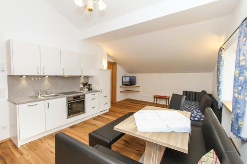a kitchen and living room with white cabinets and a table at Gästehaus Rass in Lofer