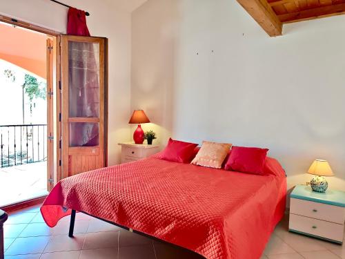 a bedroom with a red bed and a window at Villetta a pochi passi dal mare in Àrbatax