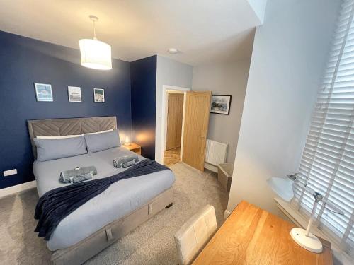 a bedroom with a large bed with blue walls at Merton Place, Southsea apartment with parking in Southsea