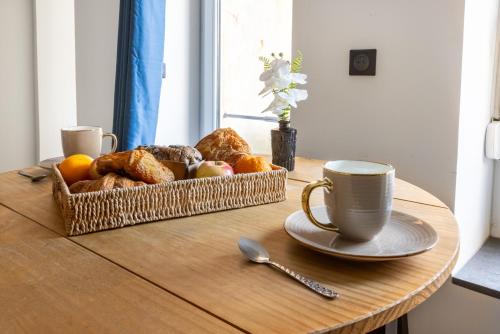 a table with a basket of bread and a cup of coffee at Le Bras d'or Apparts et Spa in Boulogne-sur-Mer