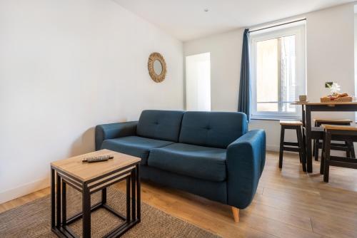 a living room with a blue couch and a table at Le Bras d'or Apparts et Spa in Boulogne-sur-Mer
