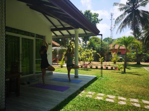 two women doing yoga outside of a house at Abhimani Bungalows in Aluthgama