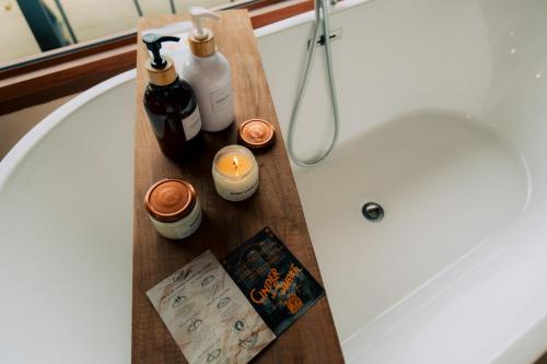 a wooden tray with bottles and candles next to a bath tub at Baan Nhuer Mek บ้านเหนือเมฆ Coffee and Desk on the Cloud in Ban Pang Klang