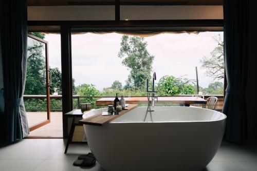 a bath tub in a bathroom with a large window at Baan Nhuer Mek บ้านเหนือเมฆ Coffee and Desk on the Cloud in Ban Pang Klang