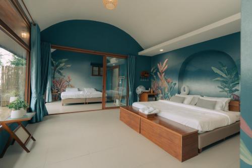a bedroom with a large bed with a blue wall at Baan Nhuer Mek บ้านเหนือเมฆ Coffee and Desk on the Cloud in Ban Pang Klang