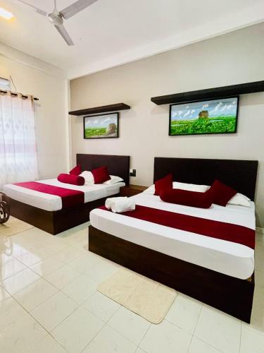 a bedroom with two beds with red pillows at Thinaya Lake Resort in Anuradhapura