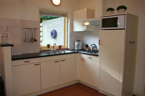 uma cozinha com armários brancos, um lavatório e um micro-ondas em Ambla em Nes